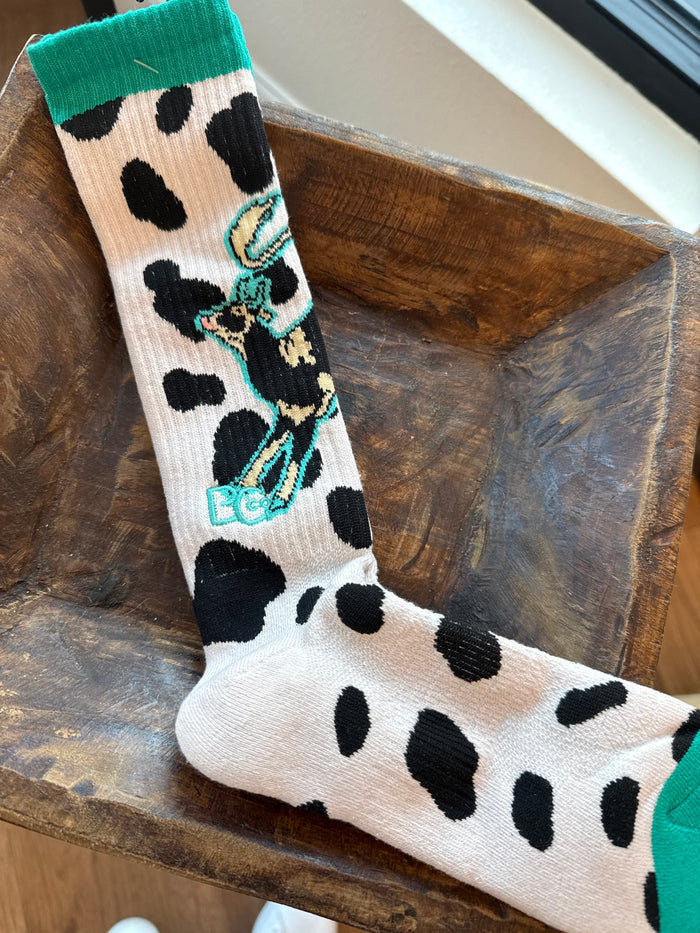 Performance socks in white with black cow spots and turquoise cactus/gear artwork.