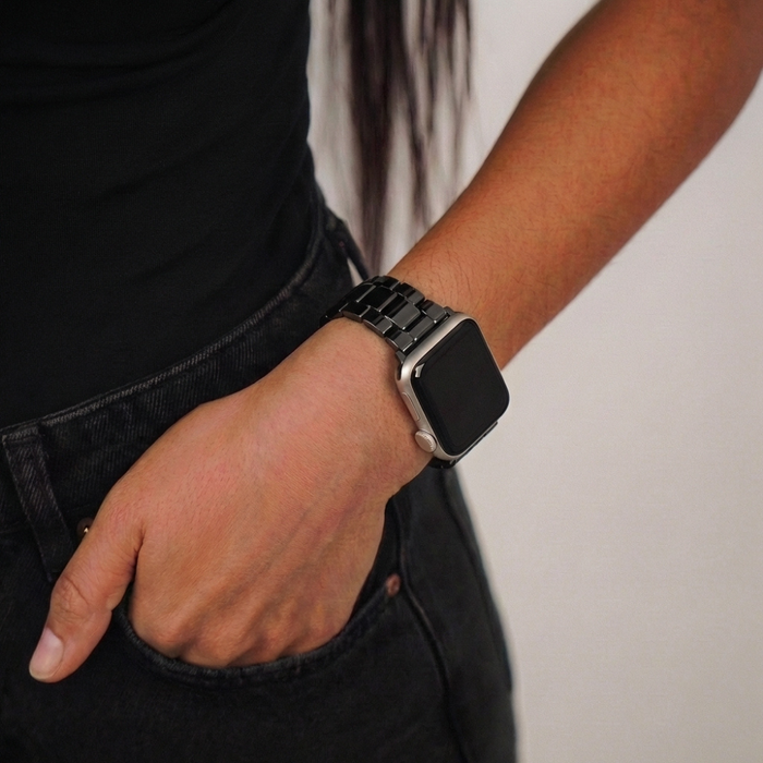 Person wearing a black Coconut Lane Apple Watch strap, hand in pocket, dressed in all black.