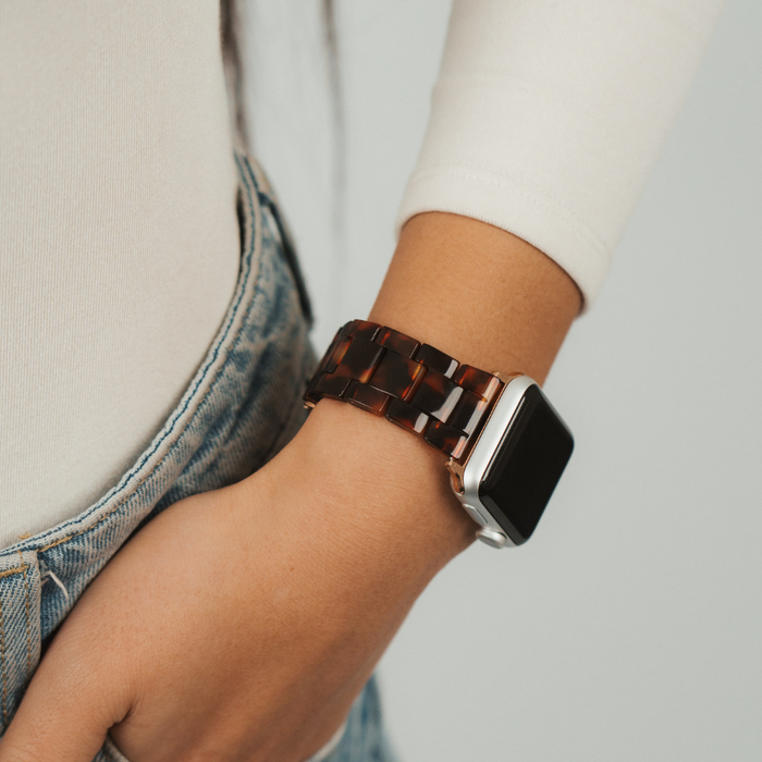 Coconut Lane Luxe Tortoiseshell Apple Watch strap on wrist, person in blue jeans with hand by their pocket.