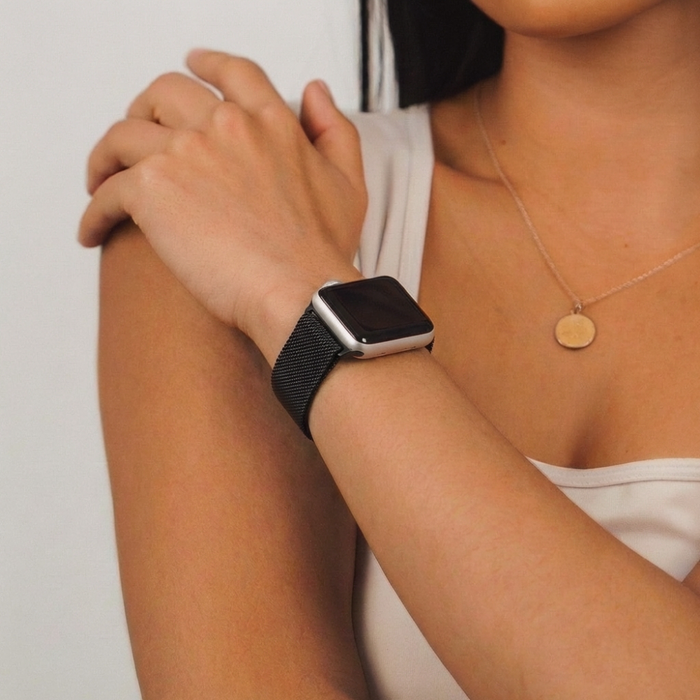 Woman showcases a black Coconut Lane magnetic chain Apple Watch strap, resting her hand on her shoulder.