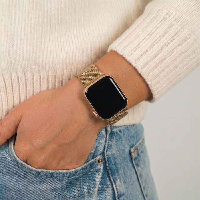 Gold smartwatch with Coconut Lane gold magnetic chain strap, worn with a cream sweater and blue jeans.