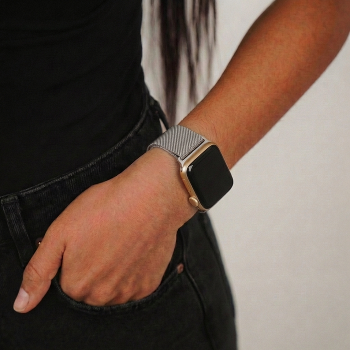 Silver magnetic chain Apple Watch strap on wrist, hand in pocket, worn with black clothing.