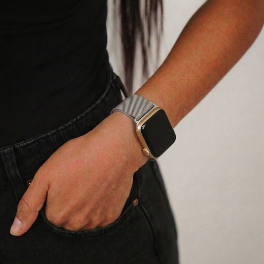 Silver magnetic chain Apple Watch strap on wrist, hand in pocket, worn with black clothing.