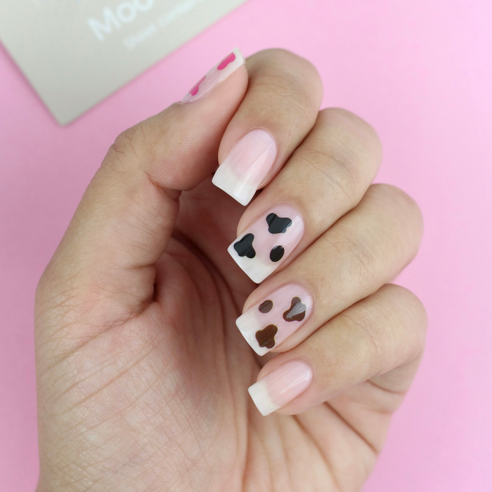 Moo-ve Over brown and black cow print decals on a sheer nude manicure with the packaging
