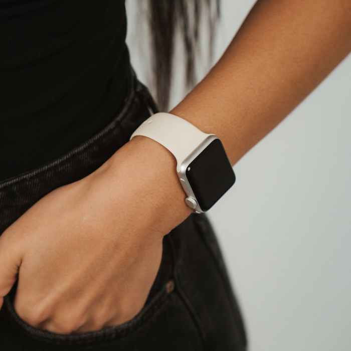 Coconut Lane NAKD Apple Watch Strap in Almond White on a wrist, paired with black jeans and a black top.