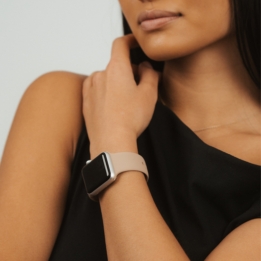 Woman in a black top wears a caramel brown Coconut Lane NAKD Apple Watch strap, hand resting on her neck.