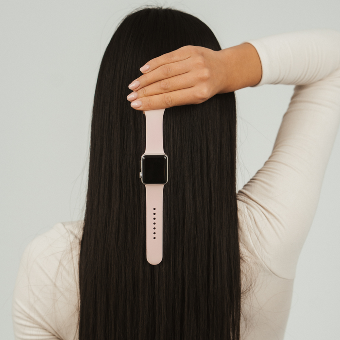Powder pink Coconut Lane NAKD Apple Watch strap held in front of long, straight black hair.