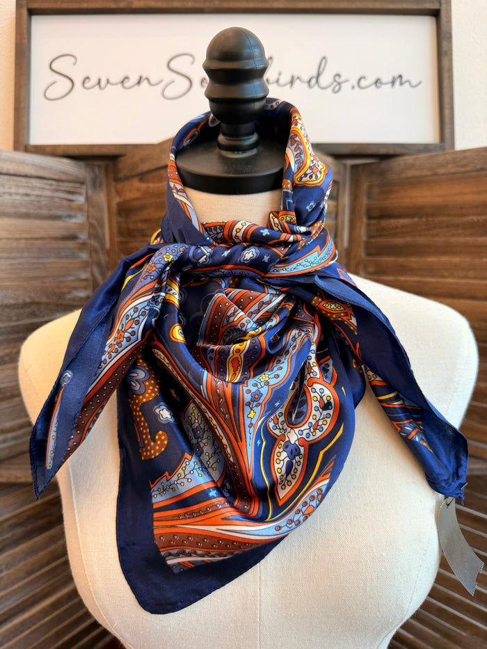 Paisley wild rag scarf in navy, orange, and white, tied in a knot on mannequin