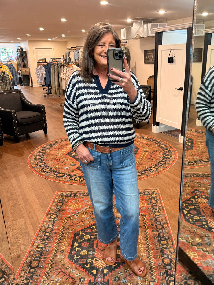 Loose knit striped sweater in navy and white with round neckline and raw-edged hem