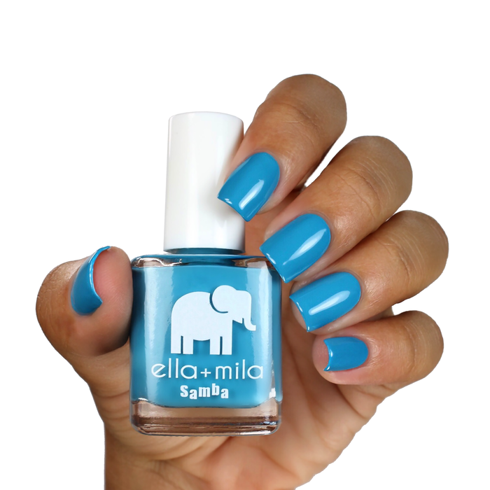 Ocean Air neon blue nail polish on a medium-deep skin tone, hand holding the bottle