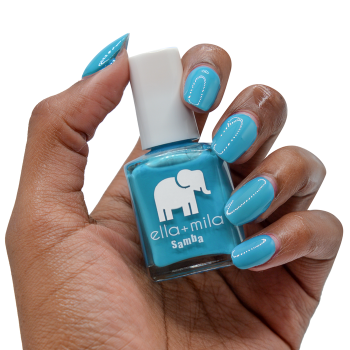 Ocean Air neon blue nail polish on a deep skin tone, hand holding the bottle