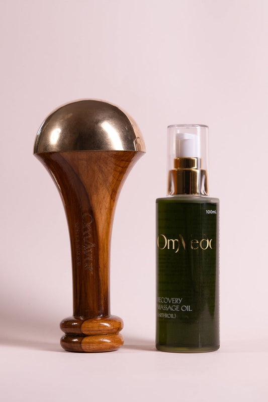 Brass-and-wood Kansa body massager with dark green massage oil bottle
