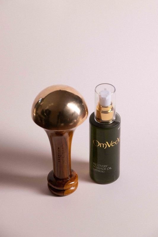 Kansa body massager and dark green massage oil bottle with gold pump top