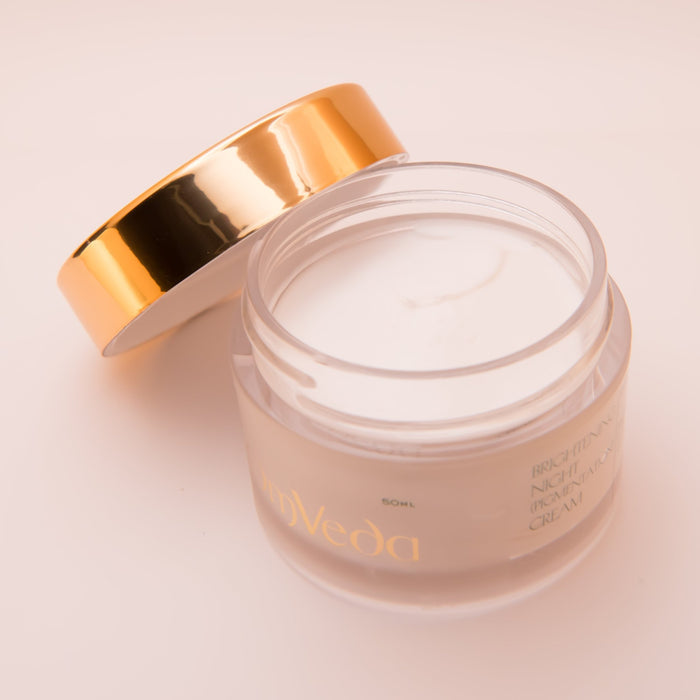 OmVeda brightening night cream jar open, white cream in jar with gold lid nearby