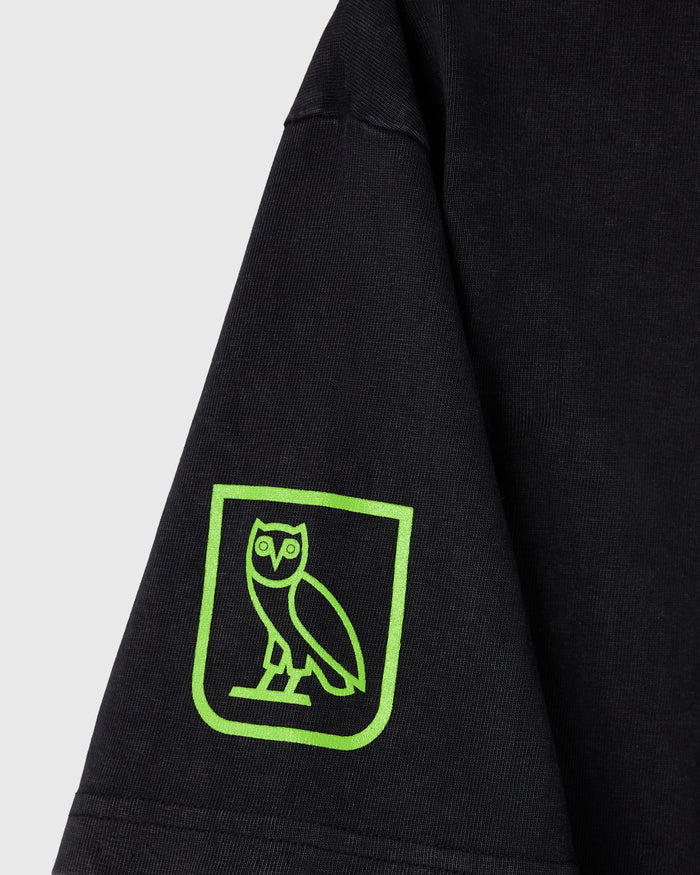 Black t-shirt with neon green owl logo in rounded rectangle on left sleeve.