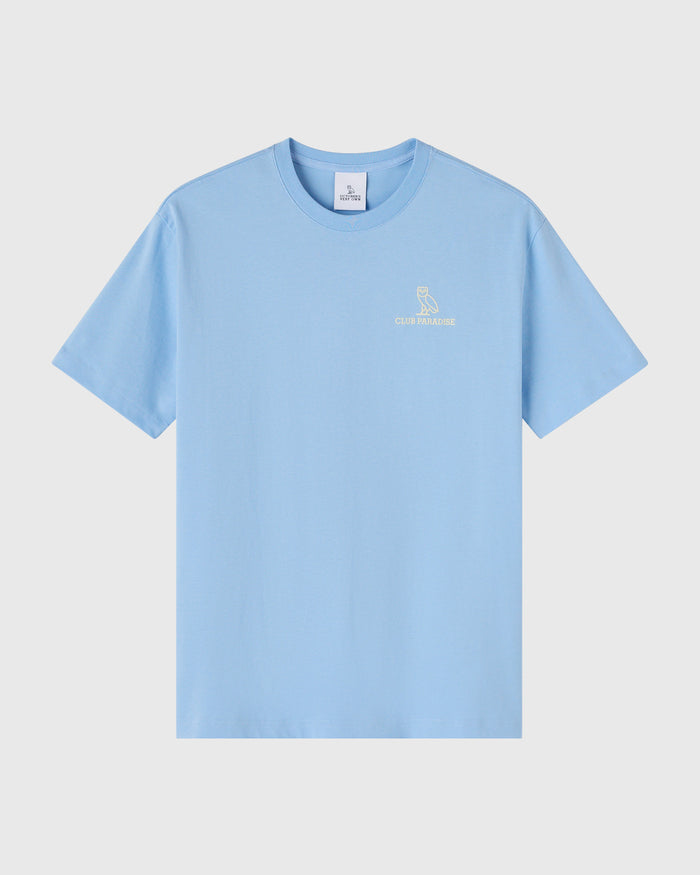Light blue t-shirt with small owl logo and "Club Paradise" text on chest.