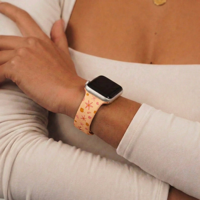 Coconut Lane Peachy Beach Apple Watch strap with peach pattern, worn with a white long-sleeve top.