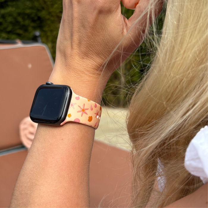 Peach and white Coconut Lane Apple Watch strap featuring star and heart shapes on a persons wrist.