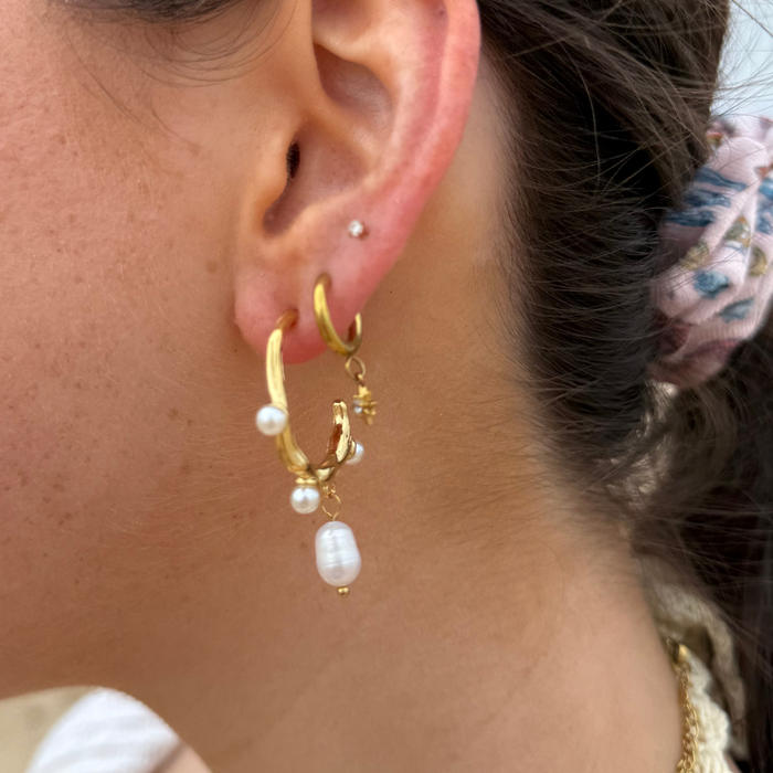 Close-up of Coconut Lane Pearl Waltz Earrings with dangling pearls on stainless steel, shown with a floral scrunchie.