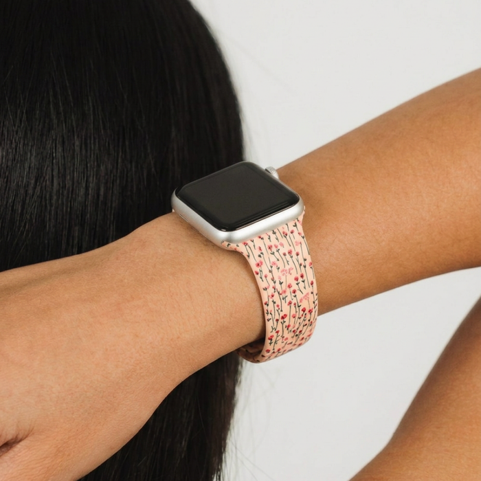 Cream Apple Watch strap with pink and green floral pattern by Coconut Lane, worn on a wrist.