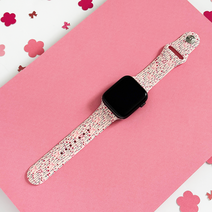 Peony Bow Apple Watch strap with floral print, shown on a pink surface with flower-shaped confetti.