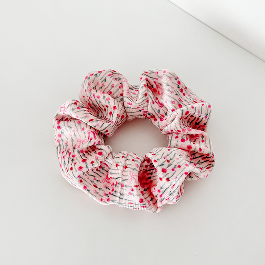 Blush pink bow scrunchie with red and purple dots, shown on a white surface.