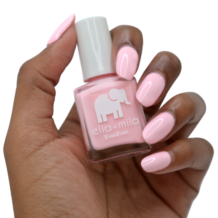 Pink Drink light pink nail polish on a deep skin tone, hand holding the bottle