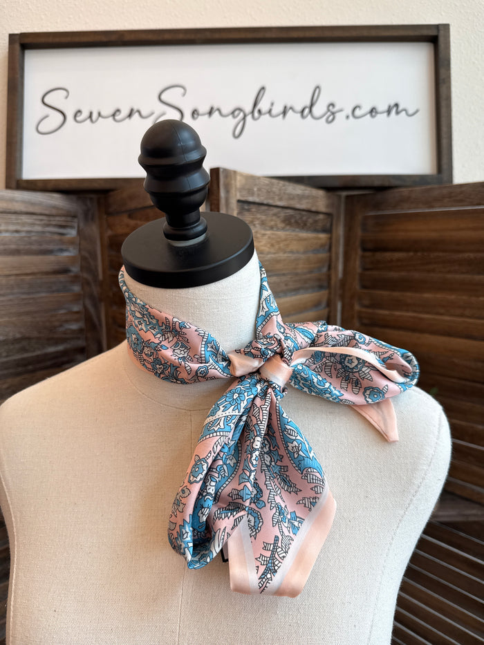 Pink and turquoise twilly scarf tied in a bow on a mannequin neck