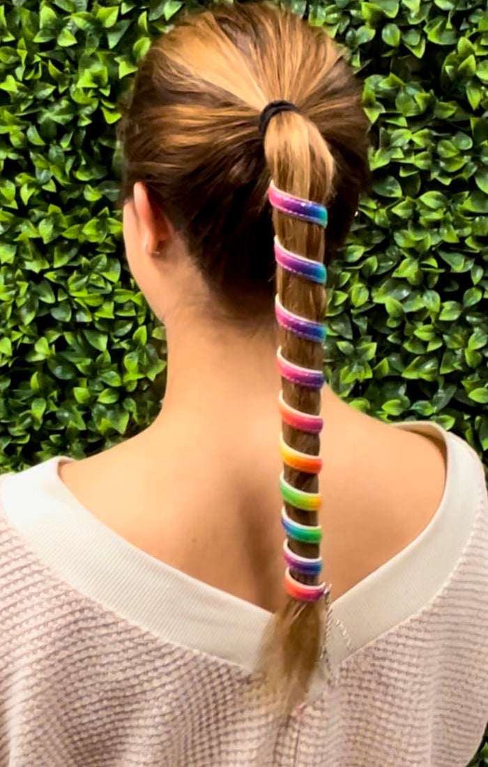 Model wearing 12 inch rainbow anodized aluminum ponytail wrap, unicorn rainbow spiral design, back view worn in a ponytail