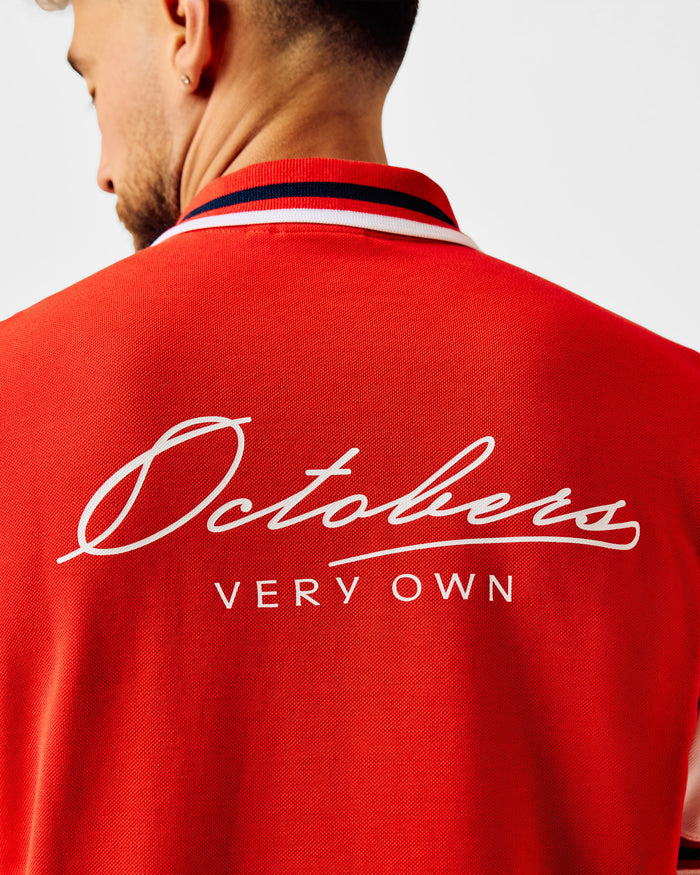Red quarter-zip polo with white and navy striped collar and back logo embroidery.