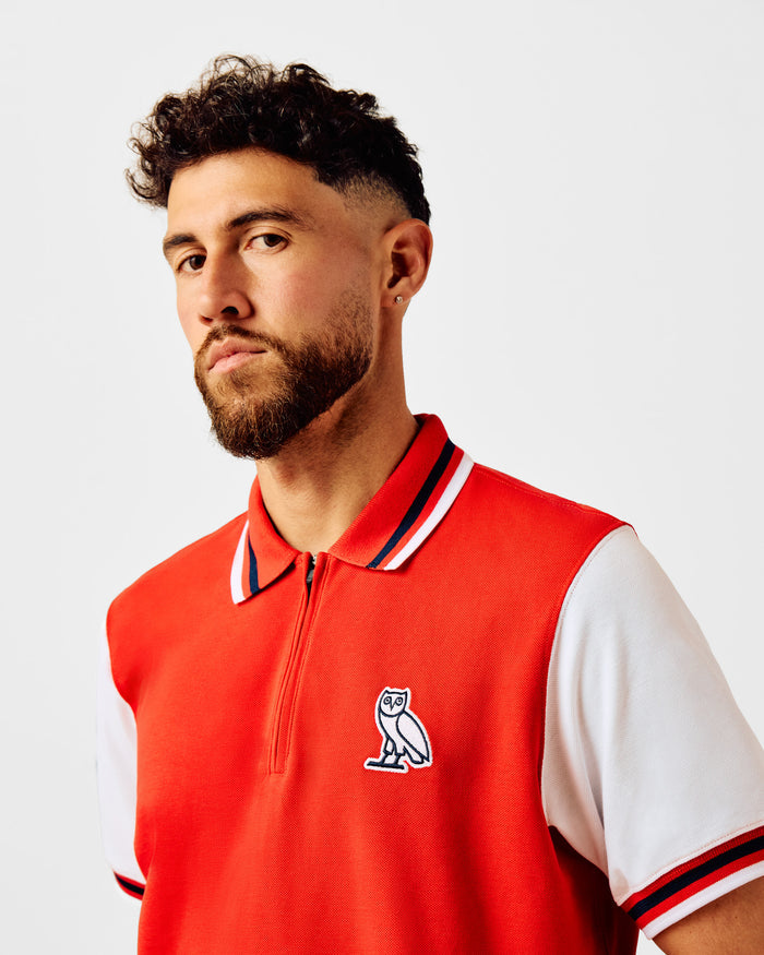 Red short-sleeve polo with white sleeves, quarter-zip neckline with striped trim, and owl embroidered on chest.