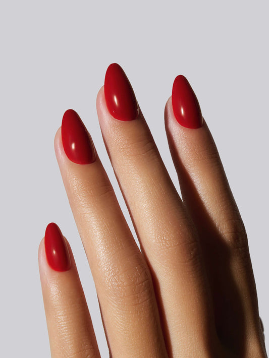Hand with red nail polish on a plain background