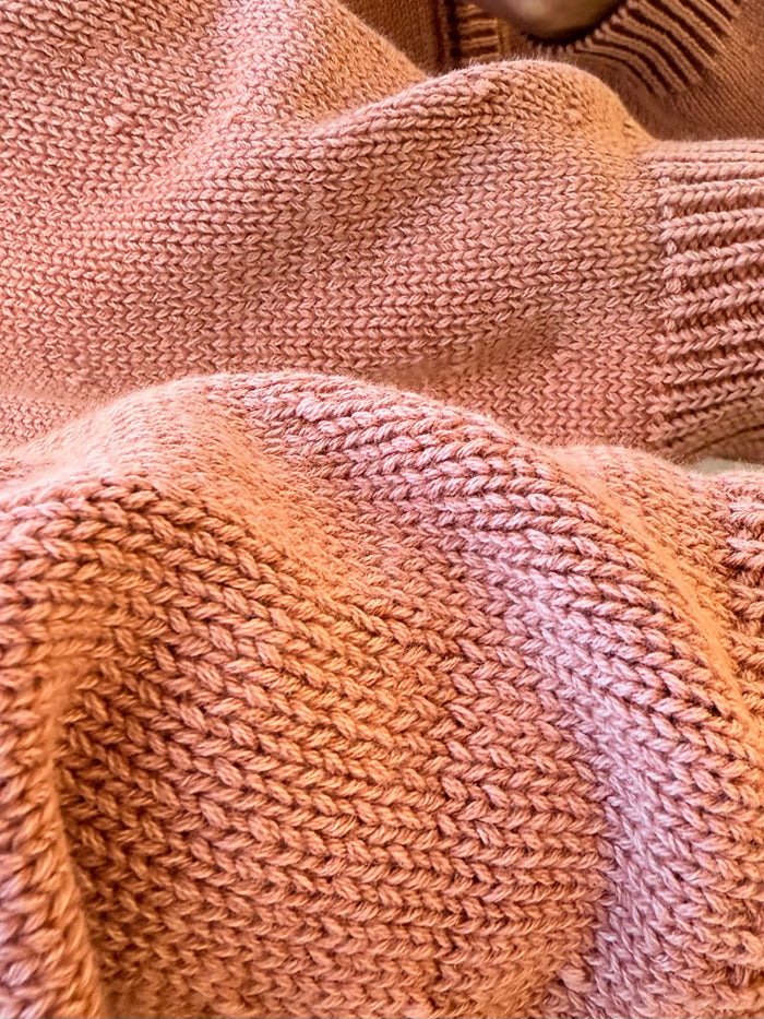 Dusty pink knit cardigan close-up with textured stitch and ribbed sleeve cuff.