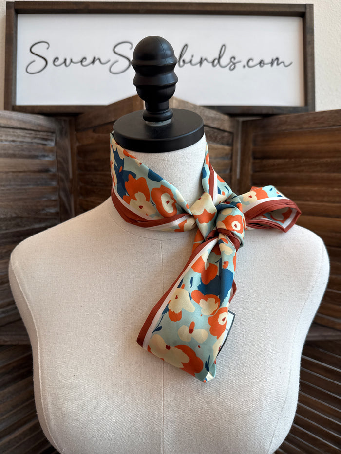 Rust and turquoise floral twilly scarf tied on a mannequin