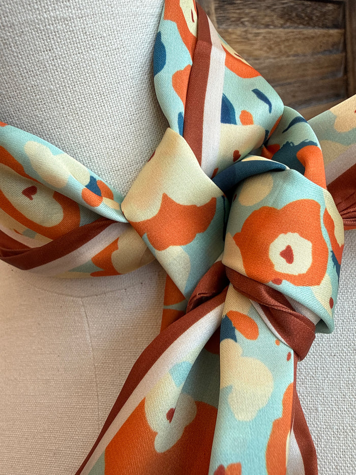 Floral twilly scarf knot detail in rust, turquoise, and cream tones