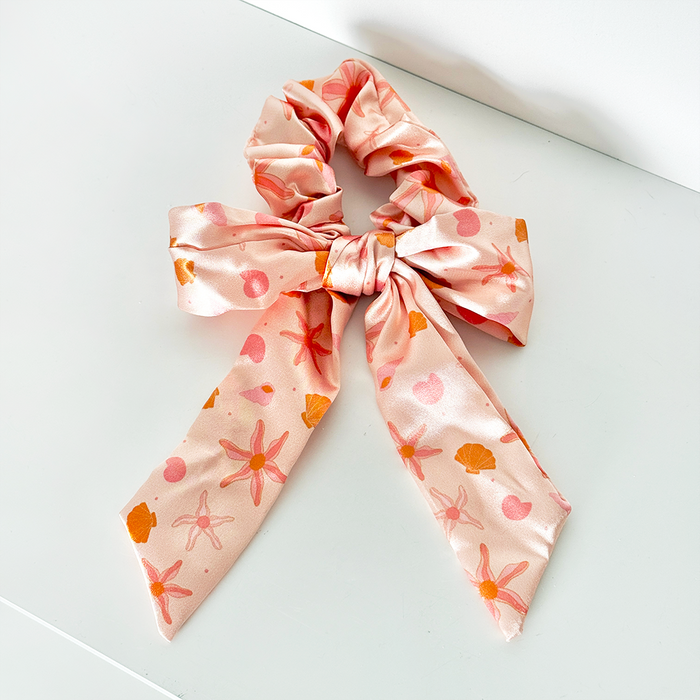 Peach satin bow scrunchie with orange starfish and seashell pattern.