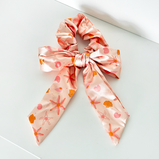 Peach satin bow scrunchie with orange starfish and seashell pattern.