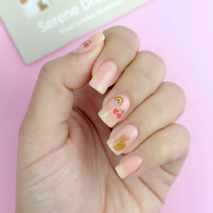 Serene Dreamin' cherry and rainbow decals on a sheer nude manicure with the packaging
