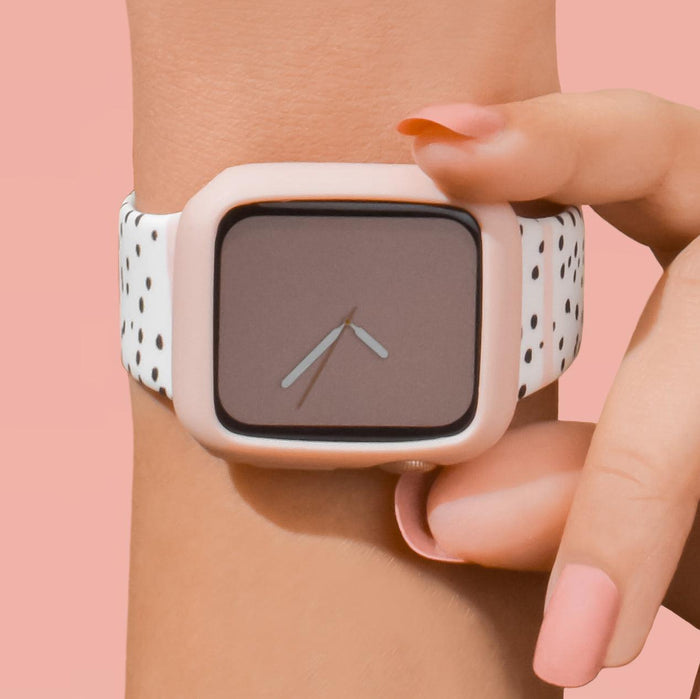 Pale pink Coconut Lane silicone Apple Watch case with a speckled band on someones wrist, pink background.
