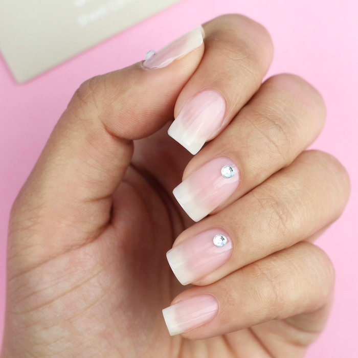 Silver Lining silver rhinestone decals on a sheer pink manicure with the packaging