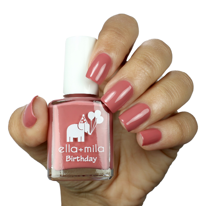 Sixth Fix dark salmon pink nail polish on a medium skin tone, hand holding the bottle