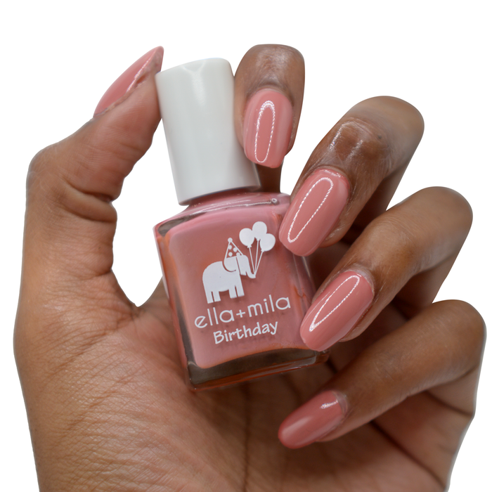 Sixth Fix dark salmon pink nail polish on a deep skin tone, hand holding the bottle
