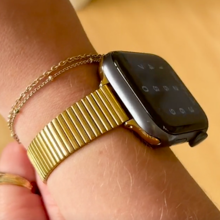 Gold Coconut Lane SLIM Fine Line Apple Watch strap on wrist, paired with a delicate gold chain bracelet.