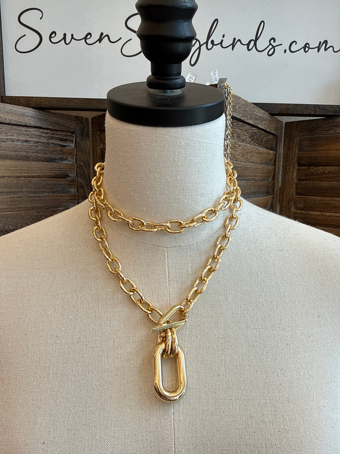 Gold-tone chunky double-link chain necklace with large oval pendant at center