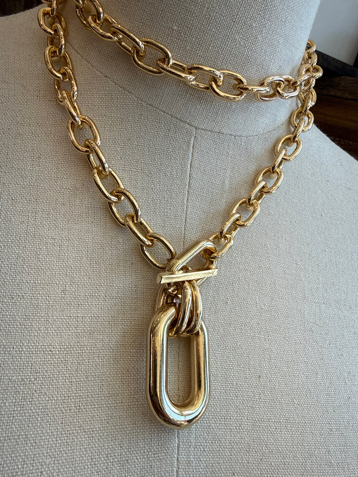 Gold-tone chunky chain necklace close-up with oval pendant and interlocking links