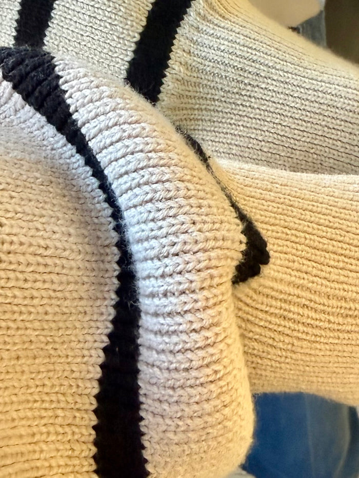 Striped knit sweater closeup: cream and black bands with denim chest pocket detail