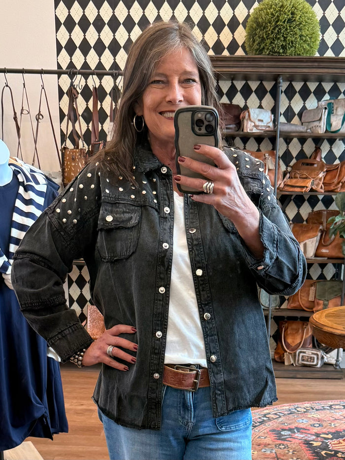 Black studded denim jacket with button front, flap pockets, and long sleeves