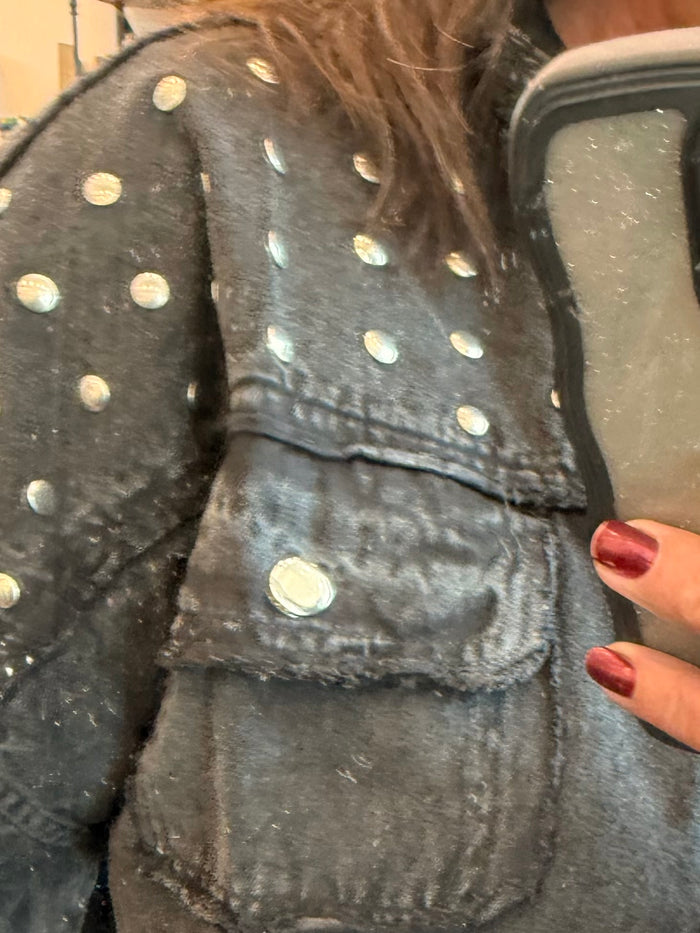 Black denim jacket close-up with gold studs on shoulder and seam details