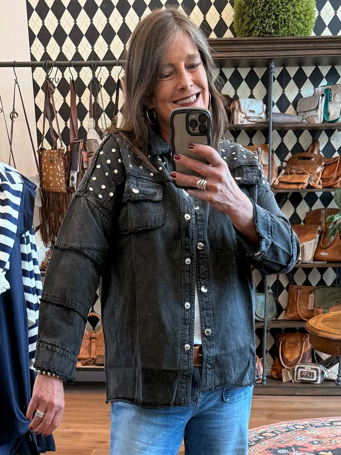 Black denim jacket with gold studs on shoulders, button front and chest flap pockets