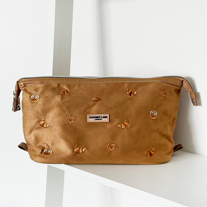 Tan suedette expandable makeup bag with gold accents, featuring Croissant Club text on the front.